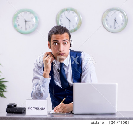 Young man receptionist at the hotel counter Young man receptionist at the hotel counter 104971001