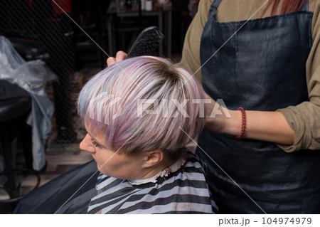 The hand of a girl of a professional salon worker combs her hair after a creative color dyeing for a client 104974979