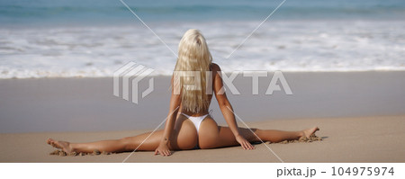 Tanned Bikini Beach Woman in Yoga Pose Doing Stretching Leg-split on Seashore 104975974