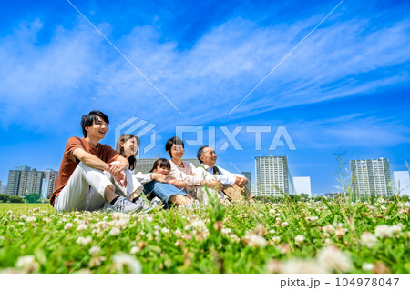 公園でくつろぐ仲良し家族三世代　体育座り 104978047