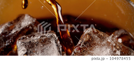 Pouring of Cola and Ice. Cola soda and ice splashing fizzing or floating up to top of surface. Close up of ice in cola water. Texture of carbonate drink with bubbles in glass. Cold drink background 104978455