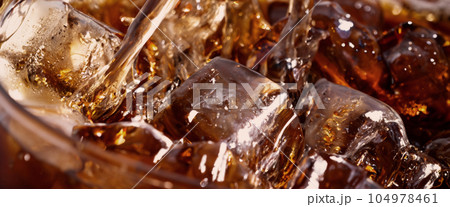 Pouring of Cola and Ice. Cola soda and ice splashing fizzing or floating up to top of surface. Close up of ice in cola water. Texture of carbonate drink with bubbles in glass. Cold drink background 104978461