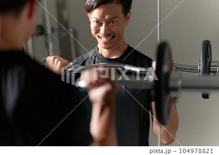 厳しい表情でウエイトトレーニングをする男性 104978821