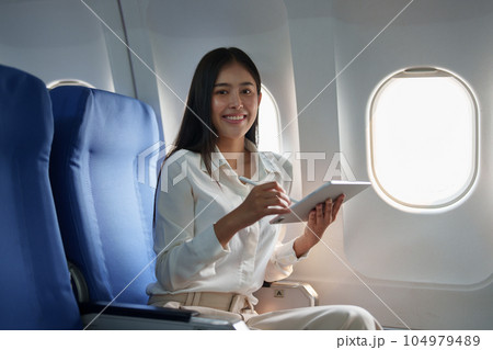 Asian attractive business woman passenger sitting on business class luxury plane while tablet computer while travel concept. 104979489