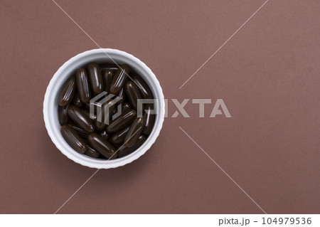 Topview Sunflower Lecithin Brown Softgel Pill Capsule In White Bowl On Brown Background. Vitamin, Dietary Supplements. Copy Space. Lecithin Benefits For Skin, Digestion, Lower Cholesterol. Horizontal 104979536