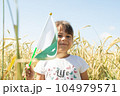 Girl waving flag of Pakistan outdoors over blue cloudy sky and golden wheat. 104979571