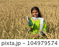 Girl waving flag of Pakistan outdoors over blue cloudy sky and golden wheat. 104979574