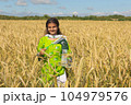 Girl waving flag of Pakistan outdoors over blue cloudy sky and golden wheat. 104979576