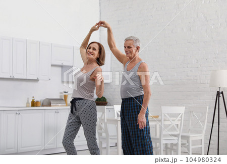 Happy senior couple dancing together in kitchen 104980324