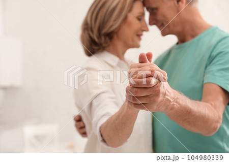 Happy senior couple dancing in kitchen, focus on hands Happy senior couple dancing in kitchen, focus on hands 104980339