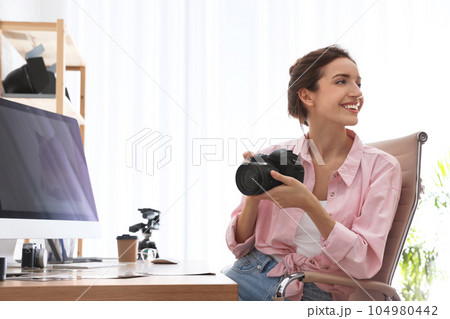 Professional photographer with camera at table in office 104980442
