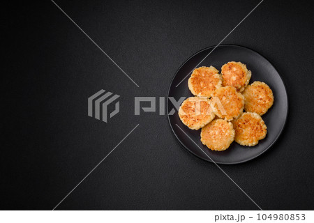 Delicious fresh cottage cheesecakes with raisins and vanilla on a black ceramic plate Delicious fresh cottage cheesecakes with raisins and vanilla on a black ceramic plate 104980853