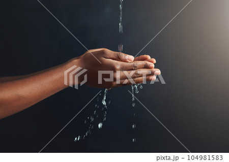 Washing hands, water and person cleaning palm for hygiene isolated in a dark or black studio background. Stream, splash and hand clean for wellness or hydration with germ protection or bacteria 104981583