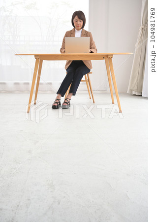 屋内の木製の机でノートパソコンの操作をする女性 屋内の木製の机でノートパソコンの操作をする女性 104981769