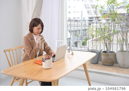 屋内の木製の机でノートパソコンの操作をする女性 屋内の木製の机でノートパソコンの操作をする女性 104981796