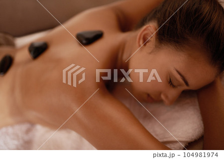 Back, hot stone massage and woman in bed with luxury service for muscle, body and relax with peace in resort. Girl, hospitality and physical therapy for spine with wellness, spa and natural healing Back, hot stone massage and woman in bed with luxury service for muscle, body and relax with peace in resort. Girl, hospitality and physical therapy for spine with wellness, spa and natural healing 104981974