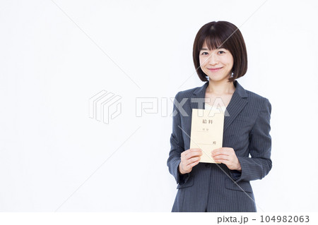 白い背景の前で給料袋を持つスーツ姿の30代の働く女性 白い背景の前で給料袋を持つスーツ姿の30代の働く女性 104982063