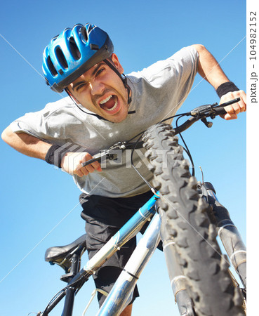 Portrait, angry cyclist and crazy face with bicycle closeup on blue sky background or cycle training, outdoor workout and healthy cardio fitness. Man, agro shout or yelling about bike workout Portrait, angry cyclist and crazy face with bicycle closeup on blue sky background or cycle training, outdoor workout and healthy cardio fitness. Man, agro shout or yelling about bike workout 104982152