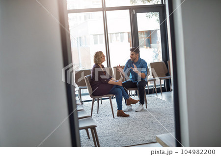 Young businessman talking to his therapist after a therapy meeting at a psychology office for mental health problems. Male employee having a discussion with a mature woman in a modern boardroom 104982200
