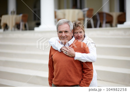 Hug, portrait and an old couple on hotel steps for travel, vacation or tourism in luxury accommodation. Love, retirement or hospitality with a senior man and woman hugging on a resort staircase Hug, portrait and an old couple on hotel steps for travel, vacation or tourism in luxury accommodation. Love, retirement or hospitality with a senior man and woman hugging on a resort staircase 104982258