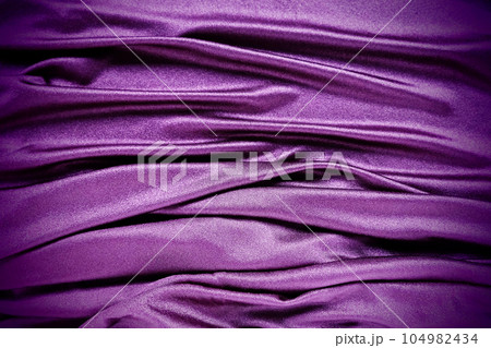 Velour fabric, similar to silk. Textiles in a folds and beautiful waves. Purple, pink, magenta shades on the drapery. Sewing material for evening dresses, furniture upholstery, curtains and interior. 104982434