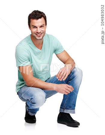 Happy, smile and portrait of a man in a studio with a casual, stylish and cool trendy outfit. Handsome, young and male model with natural fashion clothes crouching while isolated by white background. 104983032