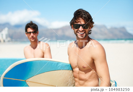 Beach, sea and man surfing friends outdoor together for travel, vacation or holiday trip overseas. Surf, summer or fun with a young male surfer in sunglasses and friend bonding on an ocean coast 104983250