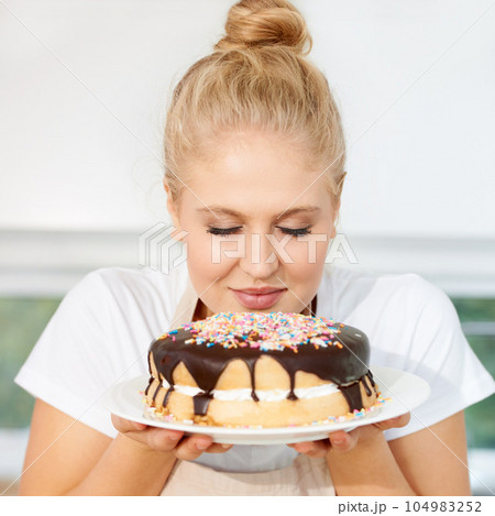 Smelling, cake and girl is holding dessert for celebration with chocolate and sprinkles with scent at a bakery. Female baker, birthday and food with pastry for party or eating a sweet meal with cream 104983252