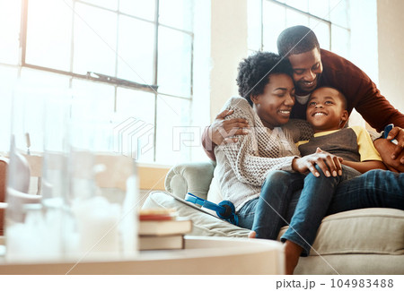 Smile, relax and family hugging on a sofa together in the living room of their modern house. Happy, love and African mother and father bonding, embracing and resting with their boy child at home. 104983488