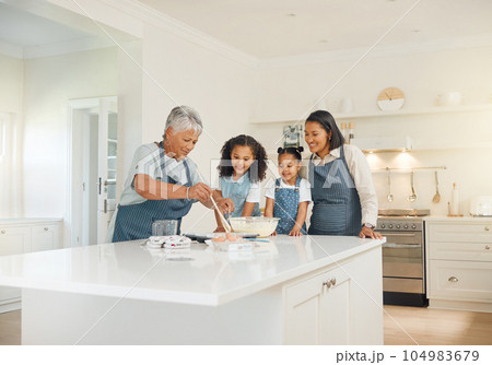 Grandmother, mom or children baking as a happy family with girl siblings learning cookies recipe at home. Mixing cake, development or grandma smiling or teaching kid to help bake with eggs or flour 104983679