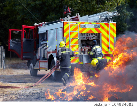 Fire, teamwork and truck with firefighter and emergency in nature for smoke, safety and explosion. Danger, fearless and training with team of men in outdoor for rescue, saving operation and action Fire, teamwork and truck with firefighter and emergency in nature for smoke, safety and explosion. Danger, fearless and training with team of men in outdoor for rescue, saving operation and action 104984683