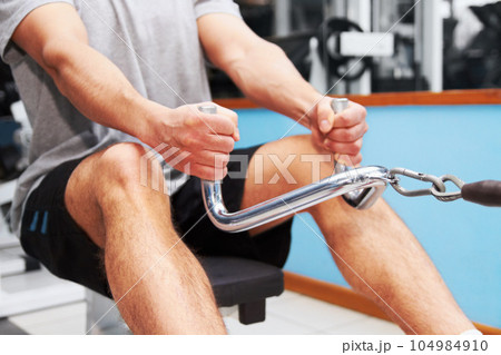 Hands, gym and rowing machine with man, fitness and workout for health, wellness and strong body. Bodybuilder guy, exercise and training with weightlifting, focus and healthy with muscle development 104984910