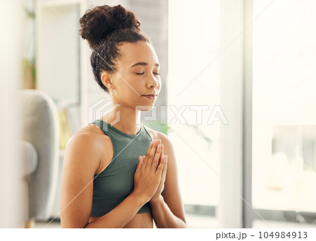 Praying hands, relax and meditation by woman in a living room for peace, wellness or mental health balance at home. Prayer pose, yoga and lady meditate in lounge for zen, healing or holistic exercise 104984913