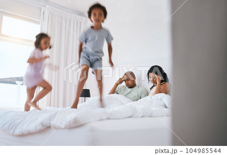 Young kids, jump and parents on bed with playing, game and excited in family house in morning. Naughty sibling children, mother and father in bedroom with bond, love and childhood development in home 104985544