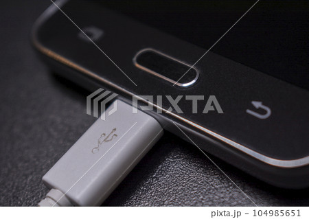 black smartphone on black background with white cable black smartphone on black background with white cable 104985651