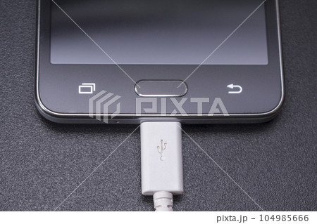 black smartphone on black background with white cable black smartphone on black background with white cable 104985666