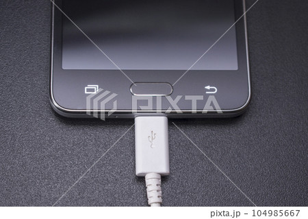 black smartphone on black background with white cable 104985667