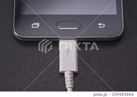 black smartphone on black background with white cable 104985669