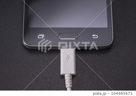 black smartphone on black background with white cable 104985671