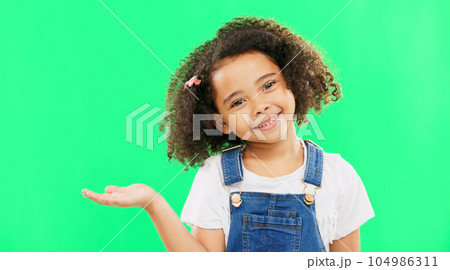 Happy, little girl and green screen with smile for product placement isolated against a studio background. Portrait of cute female kid smiling with palm of open hand showing advertisement on mockup 104986311