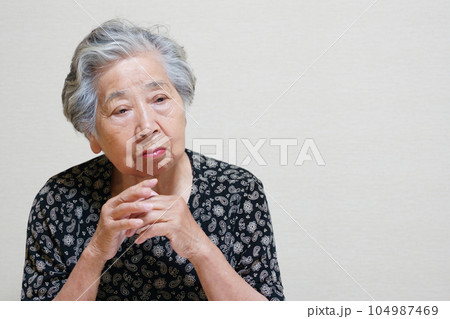 両手を組んで考え事をする高齢女性 両手を組んで考え事をする高齢女性 104987469