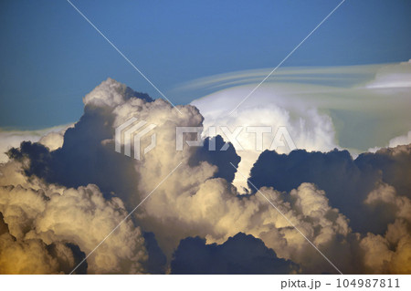 White fluffy cumulonimbus clouds forming before thunderstorm on evening sky. Changing stormy cloudscape weather at sunset White fluffy cumulonimbus clouds forming before thunderstorm on evening sky. Changing stormy cloudscape weather at sunset 104987811