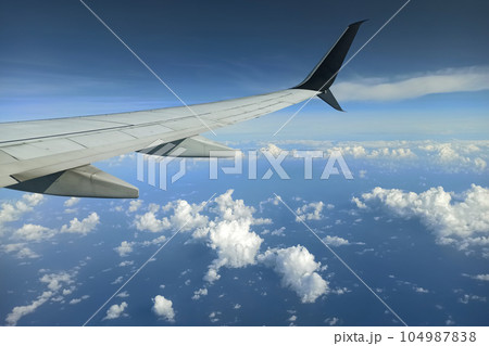 View through airplane window of commercial jet plane wing flying high in the sky. Air travelling concept 104987838