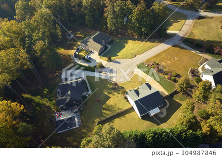 View from above of expensive residential houses between yellow fall trees in suburban area in South Carolina. American dream homes as example of real estate development in US suburbs 104987846