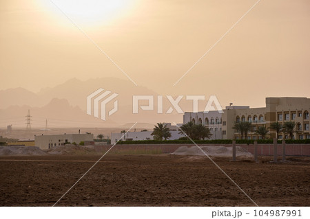 Sunset landscape with remote hotel complex against dark mountain peaks in egyptian desert Sunset landscape with remote hotel complex against dark mountain peaks in egyptian desert 104987991