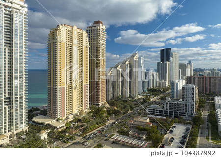 Sunny Isles Beach city with luxurious highrise hotels and condo buildings on Atlantic ocean shore. American tourism infrastructure in southern Florida Sunny Isles Beach city with luxurious highrise hotels and condo buildings on Atlantic ocean shore. American tourism infrastructure in southern Florida 104987992