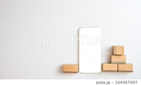 Shopping concept. Cardboard box and phone with blank screen on white background. Online shopping consumers can choose from home shopping and delivery services. with copy space. Shopping concept. Cardboard box and phone with blank screen on white background. Online shopping consumers can choose from home shopping and delivery services. with copy space. 104987997