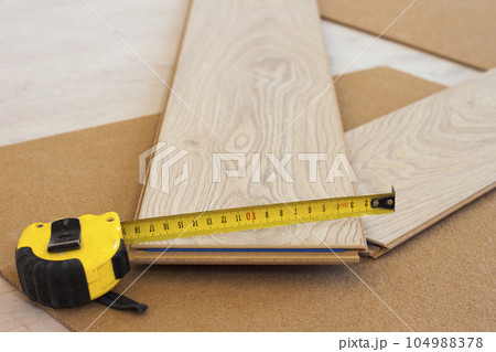 Measuring tape on laminate floor plank Measuring tape on laminate floor plank 104988378