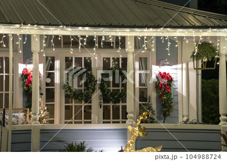 House front yard with big porch brightly illuminated with christmas decorations. Outside decor of florida family home for winter holidays House front yard with big porch brightly illuminated with christmas decorations. Outside decor of florida family home for winter holidays 104988724