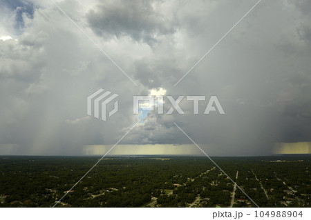 Dark stormy clouds forming on gloomy sky during heavy rainfall season over suburban town area 104988904